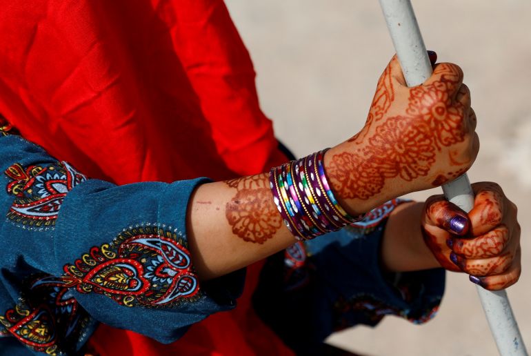An Afghan girl with henna patterns on her hands rides on a swing during the first day of Eid al-Adha, in Kabul, Afghanistan [File: Mohammad Ismail/Reuters]
