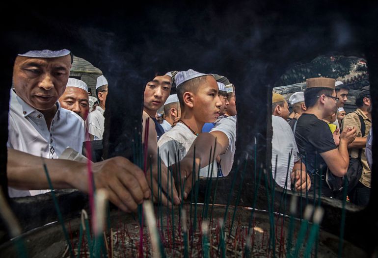 Chinese Hui Muslim men light incense at the ‘Sheiks Tombs’ after Eid prayers at the historic Niujie Mosque in Beijing, China [File: Kevin Frayer/Getty Images]
