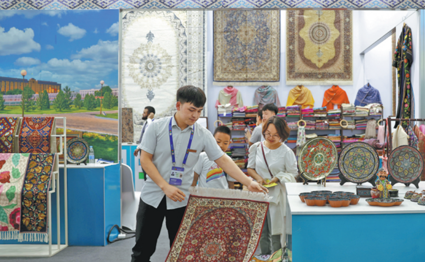 Chinese guests pick out Uzbek blankets at the expo on Aug 28. YU JING/CHINA NEWS SERVICE
