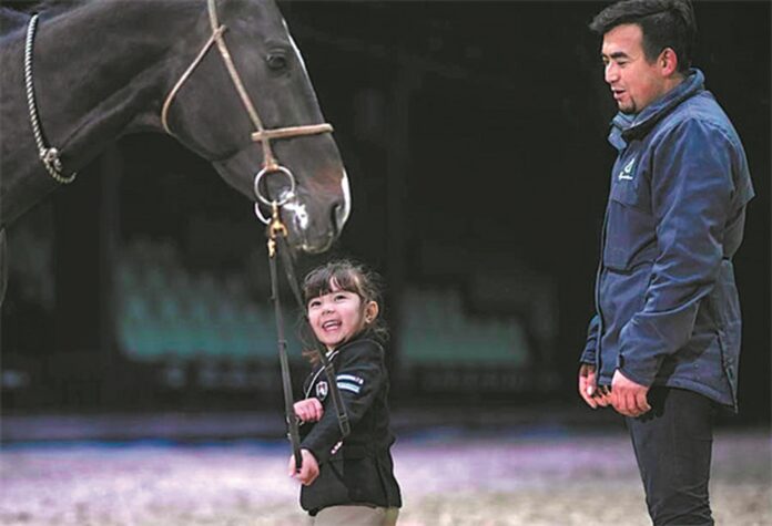 Shakla (left) trains a horse under the guidance of her father Xirzat Nurmu